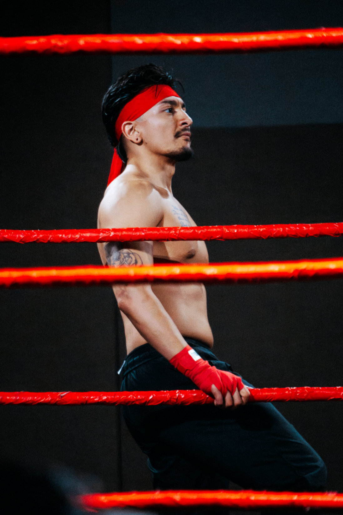 Red-banded fighter posing between the ropes